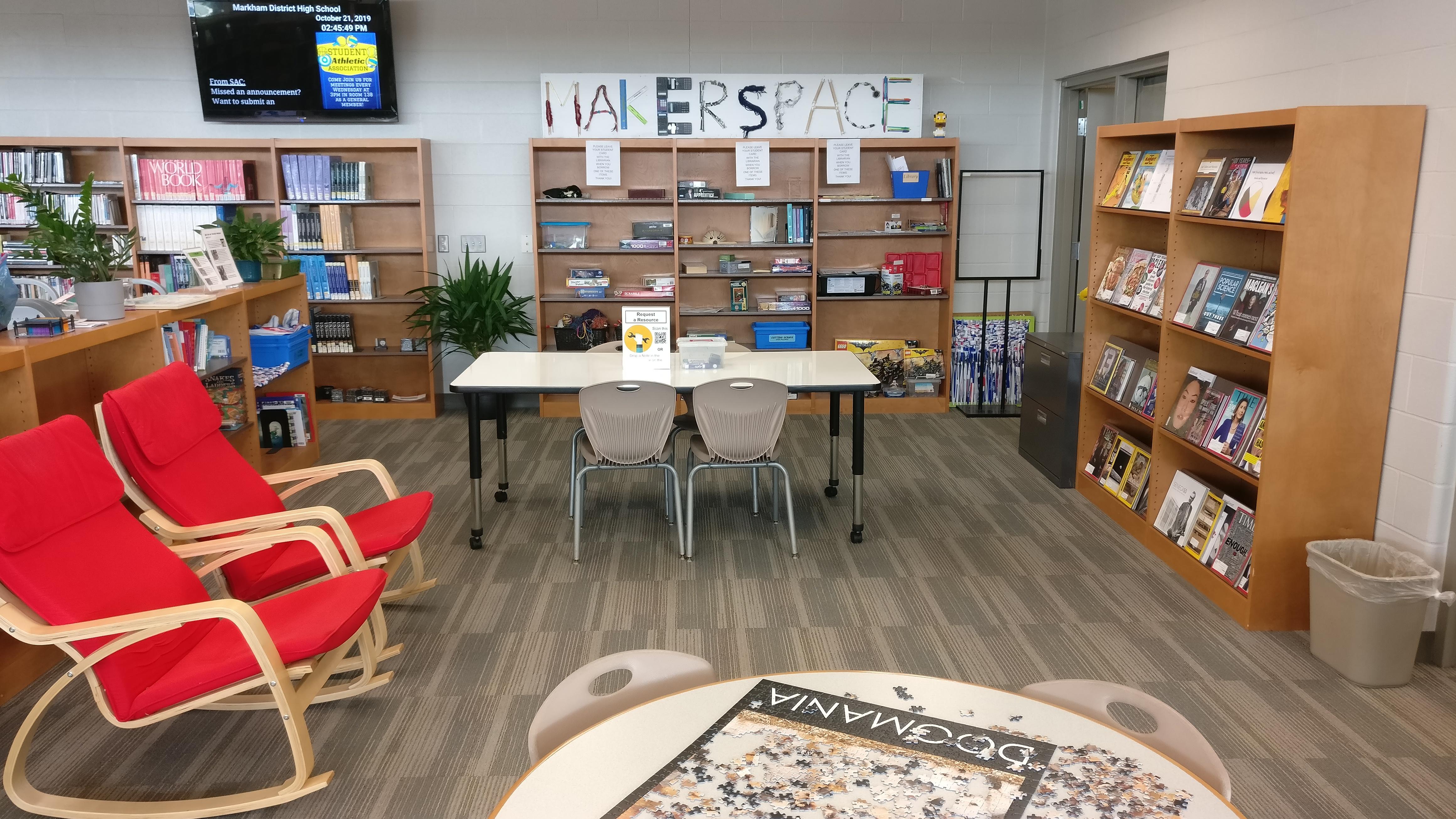 Maker space area with tables and bookshelves of puzzles and games.